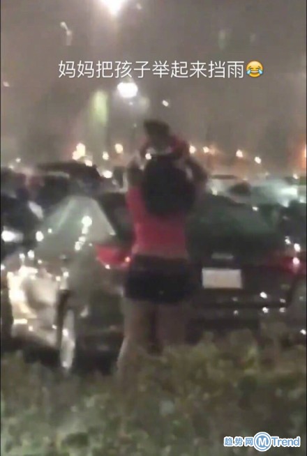 妈妈把孩子举起来挡雨 绝对是亲生的